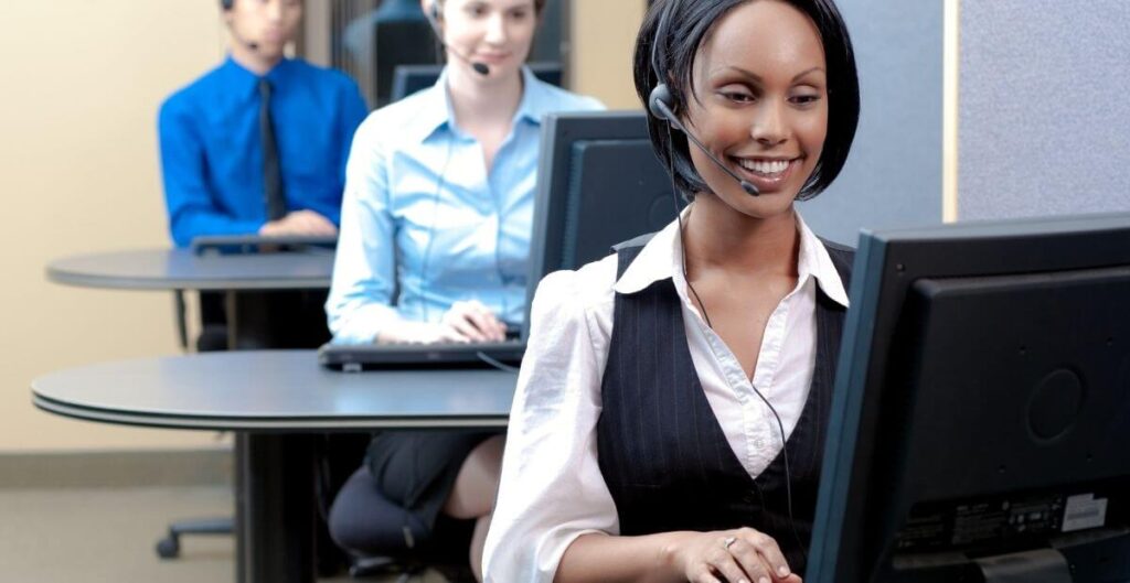 Contact centre vs. call centre: a female support agent smiling while working on her laptop