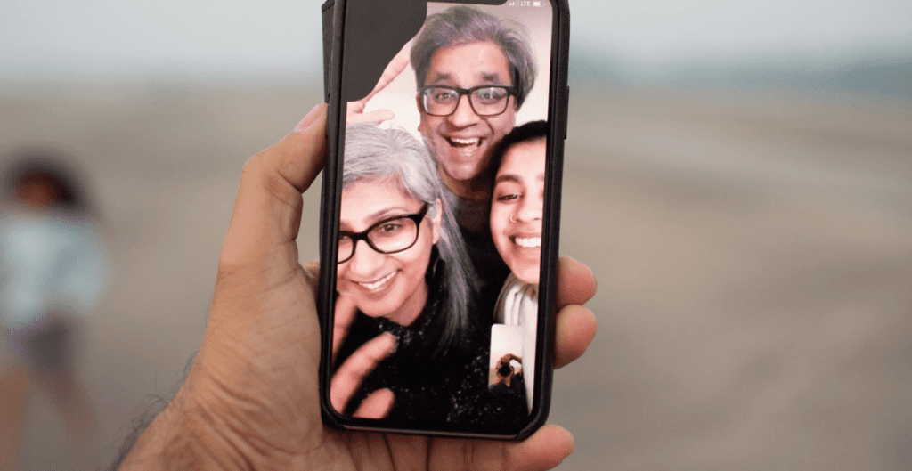 web conferencing example of a man holding a phone with family members on video call - Photo by Raj Rana on Unsplash