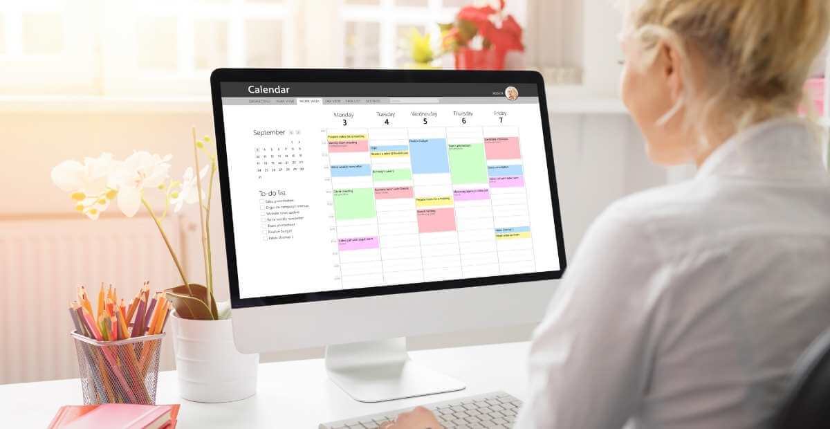 A woman on her computer looking at her digital calendar while scheduling a recurring meeting