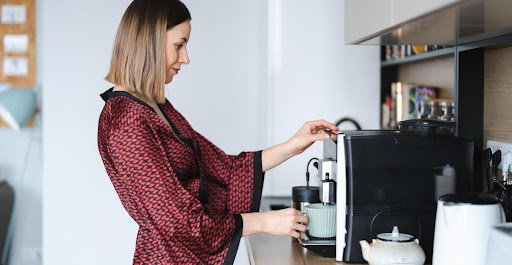 Extra amenities | A female hotel guest making fresh coffee in her room