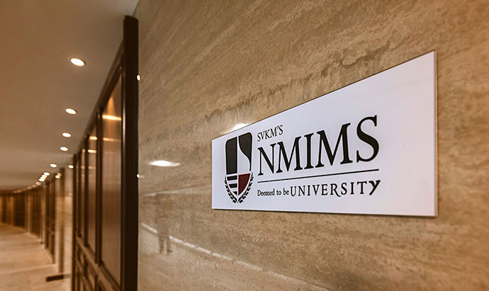 Header Image | A placard is placed on the wall. It reads NMIMS 